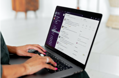 Man typing into Slack on a laptop